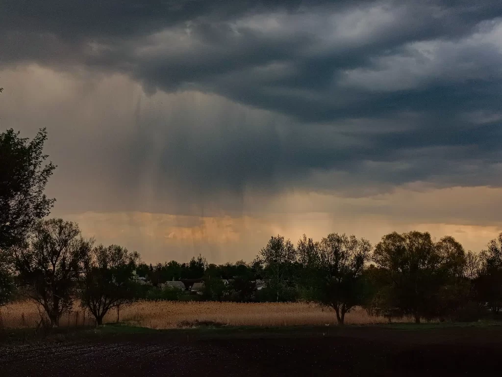 Dark storm clouds gather over a rural field, hinting at approaching rain. Captured in detail, this scene evokes a sense of impending weather change